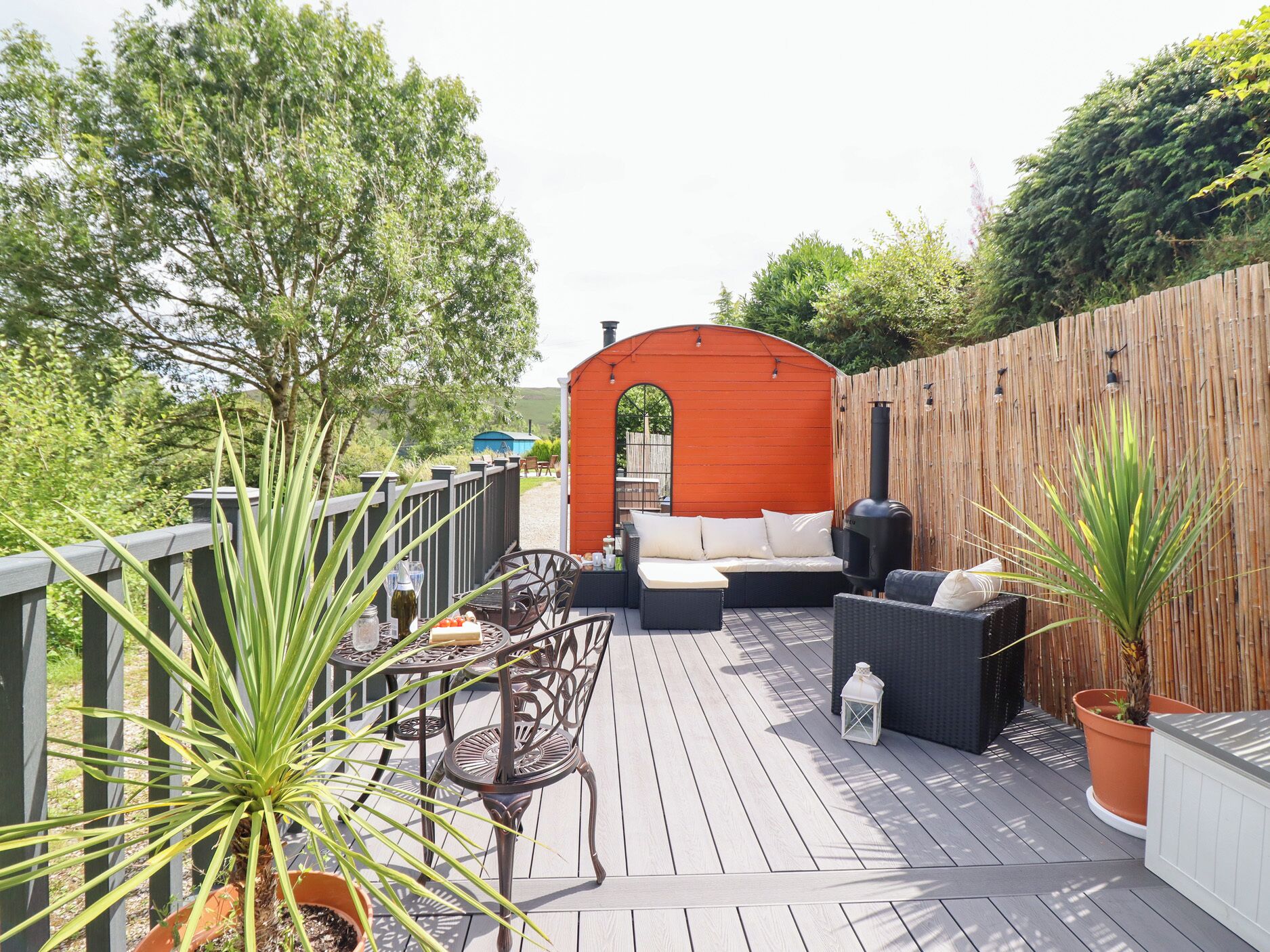 Une terrasse dotée de mobilier d’extérieur, d’un espace barbecue et d’une clôture en bois.