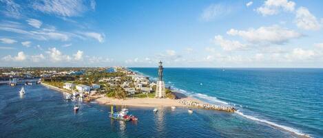 A coastal town with a lighthouse, boats, and a beach.