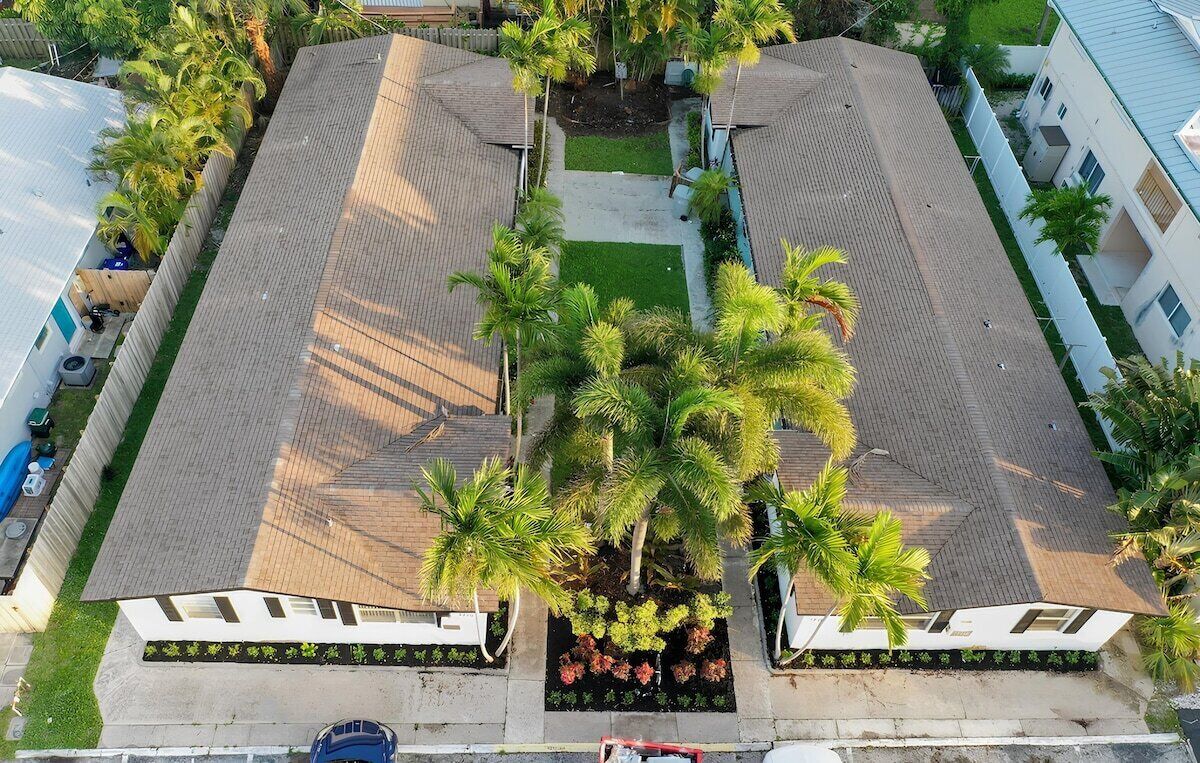 A multi-story building with a central courtyard surrounded by trees and a paved walkway.