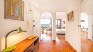 Un corridoio con un tavolo consolle in legno, una lampada da scrivania verde e un quadro appeso al muro.