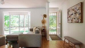 A spacious living room with a large window, a sofa, a bench, and a door leading to a balcony. - Nirvana - Escape from urban chaos to relish all the region has in store. (Porepunkah)
