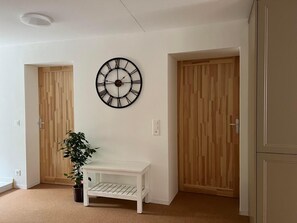 A cozy corner with a bench, potted plant, and large wall clock.