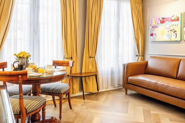 A dining area with a wooden table and chairs, a coffee pot, and a vase of flowers. - Orly Suites (Santiago)
