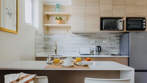 Een moderne keuken met een centraal eiland, een magnetron, een broodrooster en een koelkast.
