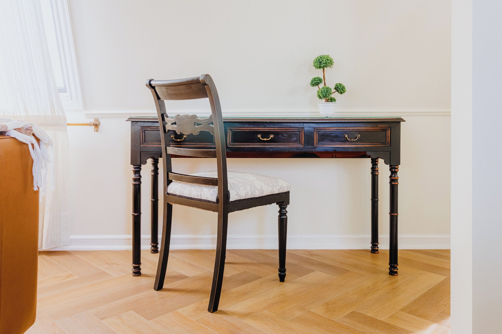 Un escritorio de madera oscura con cajones y una silla con asiento acolchado.
