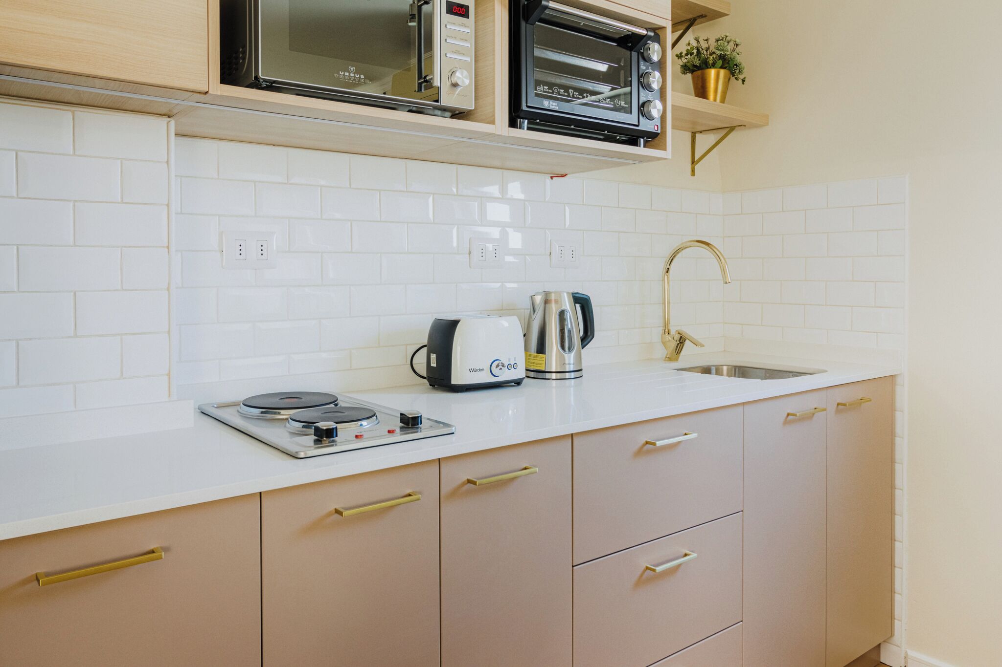 A modern kitchen with white subway tiles, stainless steel appliances, and light wood cabinets.
