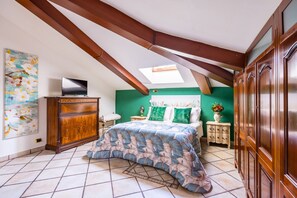 Cozy bedroom with a loft-style design, featuring a large bed, wooden nightstand, and a television mounted above.
