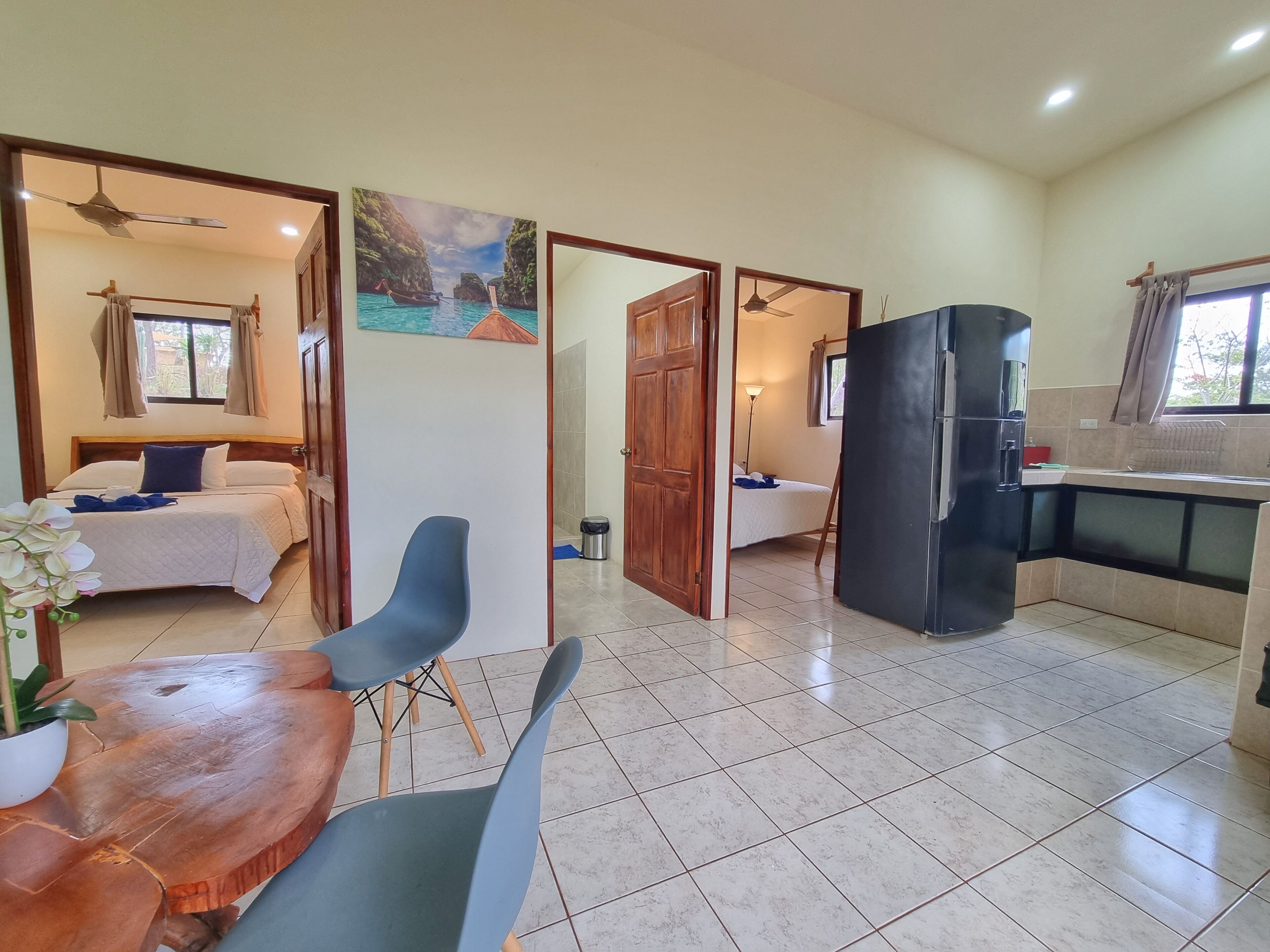 Habitación de hotel con cama, escritorio, silla, mesa de comedor y zona de cocina.