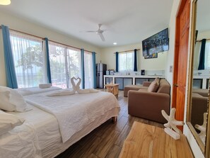 A hotel room with a large bed, a sofa, a small table, and a kitchenette. - Pinilla Highlands (Tamarindo)