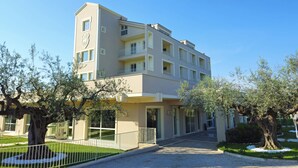 A multi-story hotel with a modern design, featuring a central entrance, balconies on each floor, and a surrounding garden with mature trees. - Giardino Dei Principi (Citta Sant'Angelo)