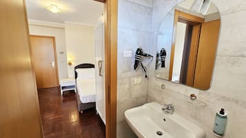 Un bagno d'albergo con lavandino, specchio e asciugacapelli.