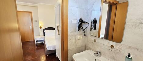 Ein Badezimmer im Hotel mit Waschbecken, Spiegel und Föhn.