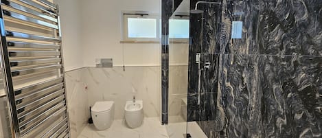 Un baño moderno con cabina de ducha de vidrio, inodoro y bidé.