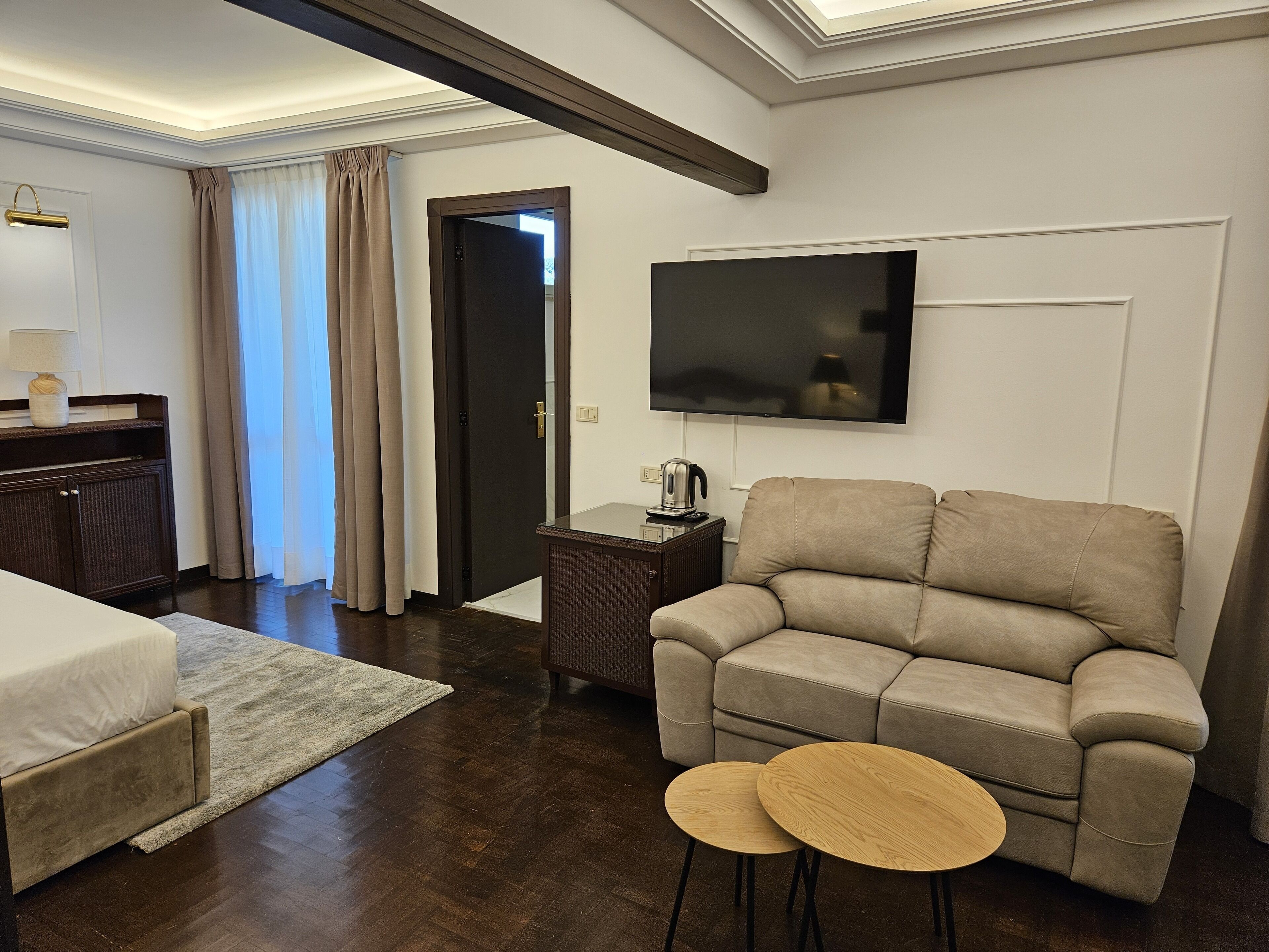 Ein modernes Hotelzimmer mit einer Couch, einem Fernseher, einem kleinen Tisch und einem Bett.