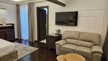 Una habitación de hotel moderna con sofá, televisor, una mesita y cama.