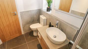 A modern bathroom with a wooden door, a toilet, a sink, and a mirror.