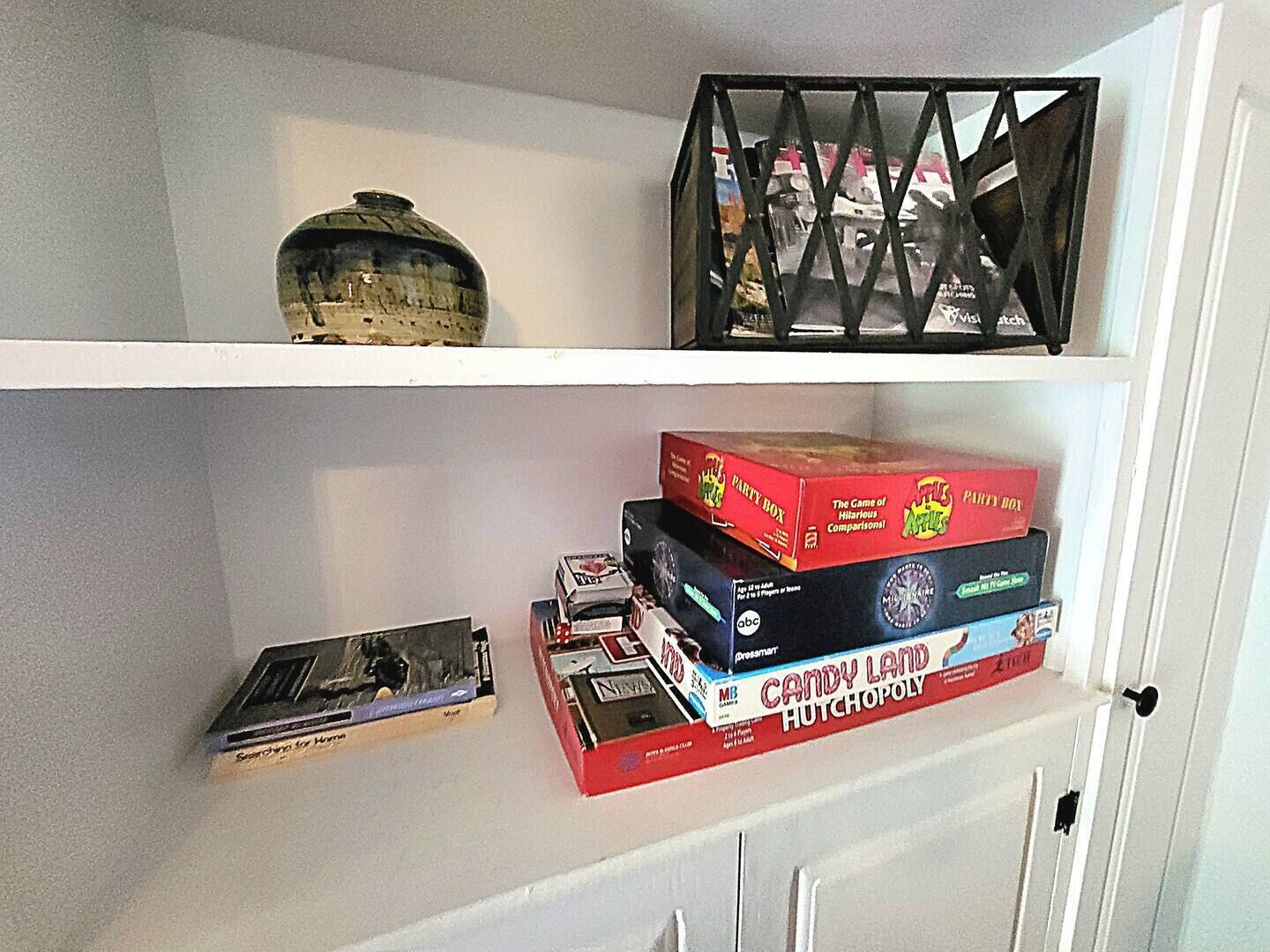 Une étagère avec un appareil photo ancien, une boîte de jeu et un objet décoratif.