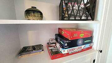 Une étagère avec un appareil photo ancien, une boîte de jeu et un objet décoratif.