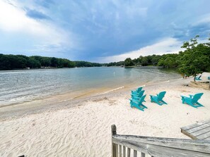Une plage avec une terrasse en bois et des chaises turquoise.