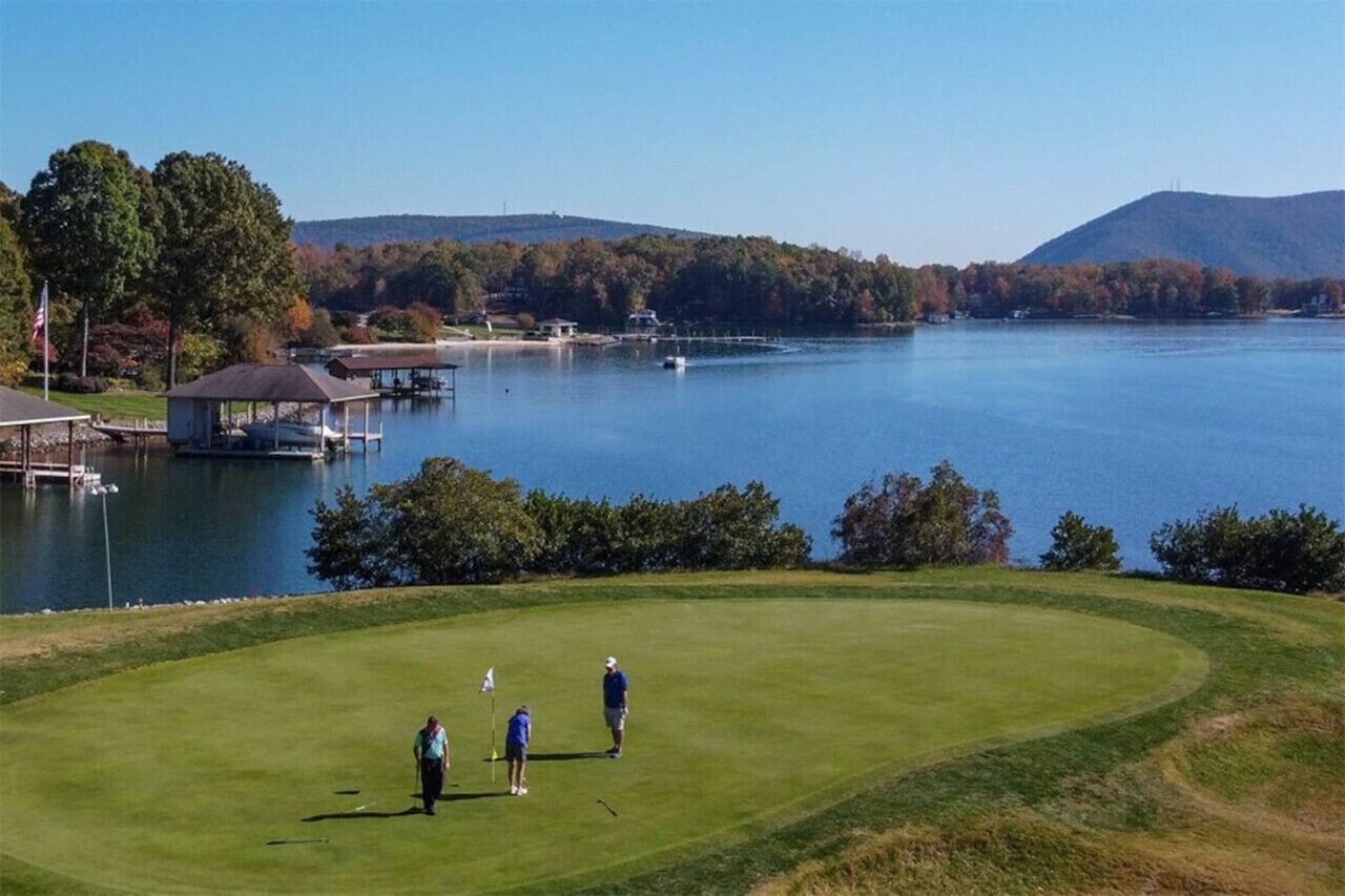Un parcours de golf avec un plan d’eau, un quai et des arbres en arrière-plan.