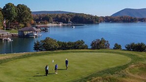 A golf course with a water body, dock, and trees in the background.