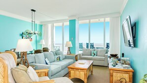 A spacious living room with two sofas, a coffee table, and a TV mounted on the wall. - Seaside Family Oasis Hideaway (Galveston)