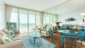 Ein geräumiges Wohnzimmer mit großem Glastisch, bequemen Sitzgelegenheiten und Meerblick.