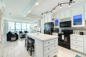 Een moderne keuken met witte kastjes, een centraal eiland en een groot raam met uitzicht op een mooi landschap.