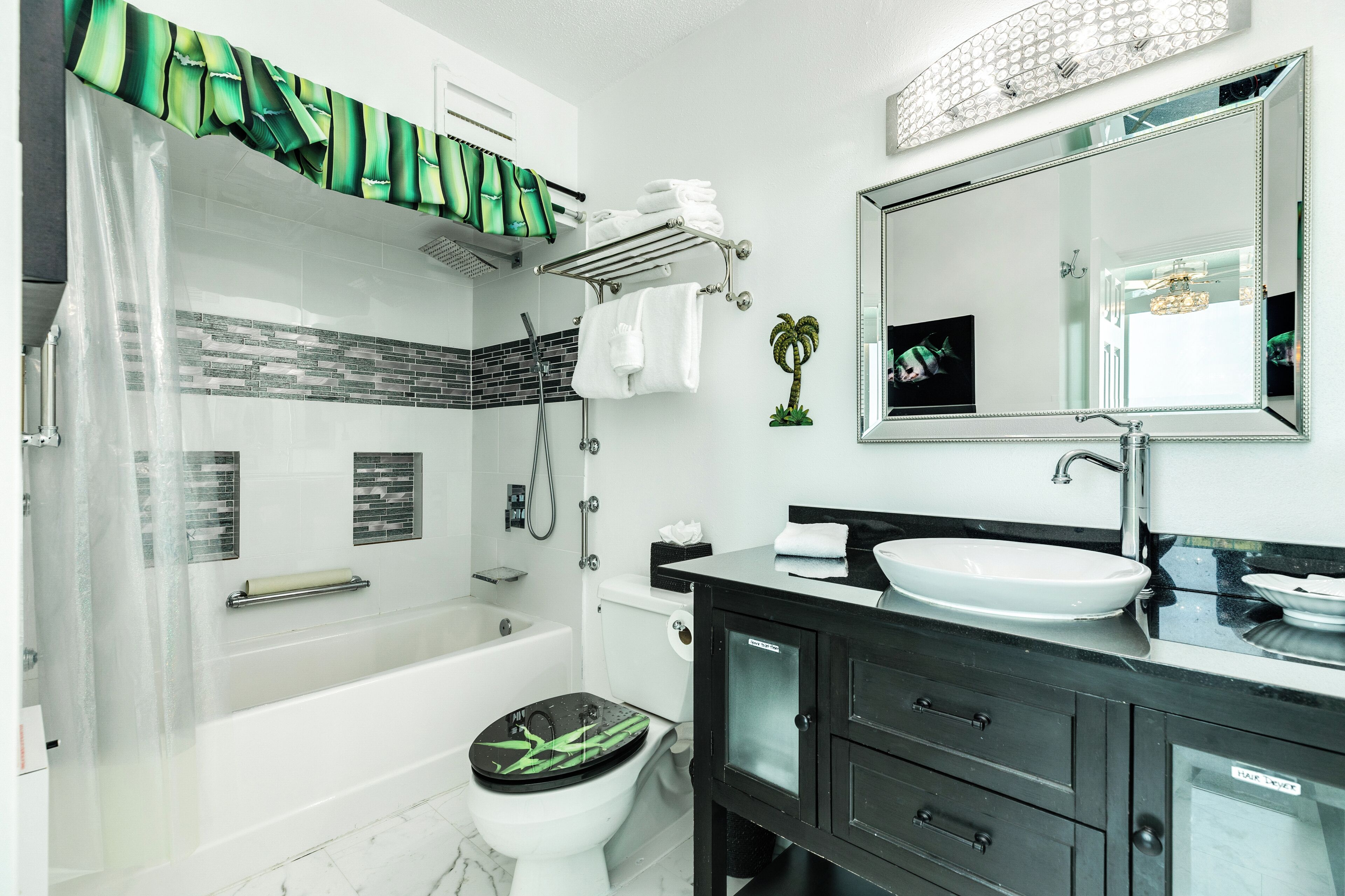 Un baño moderno con bañera, inodoro y tocador con un espejo grande.