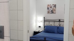 A bedroom with a bed, a nightstand, a wall-mounted air conditioner, and a painting. - Guest House L'orto di Antonio, surrounded by greenery a few steps from the sea  (Palinuro)