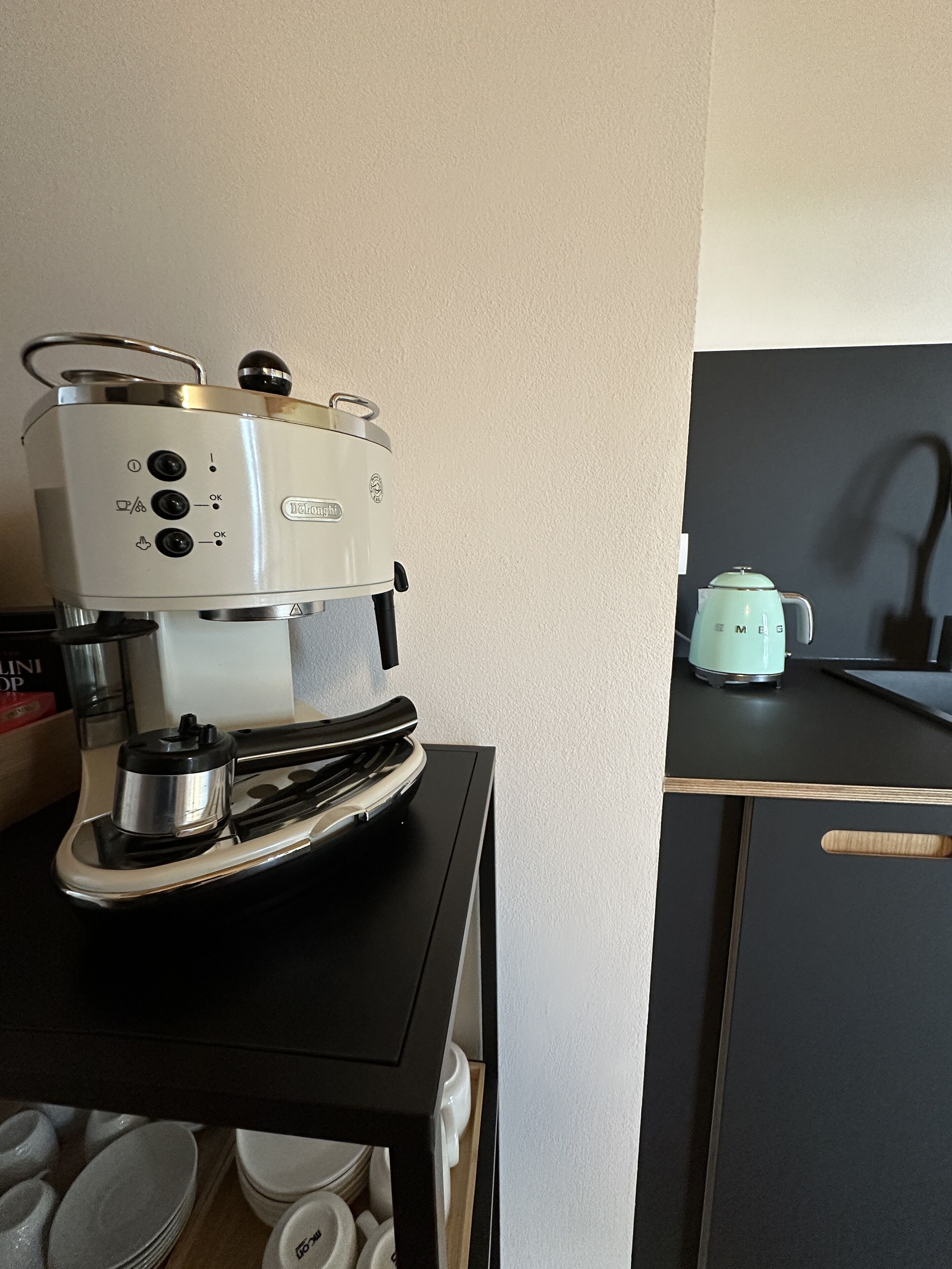 A kitchen with a coffee maker on a black countertop and a kettle on the stove.
