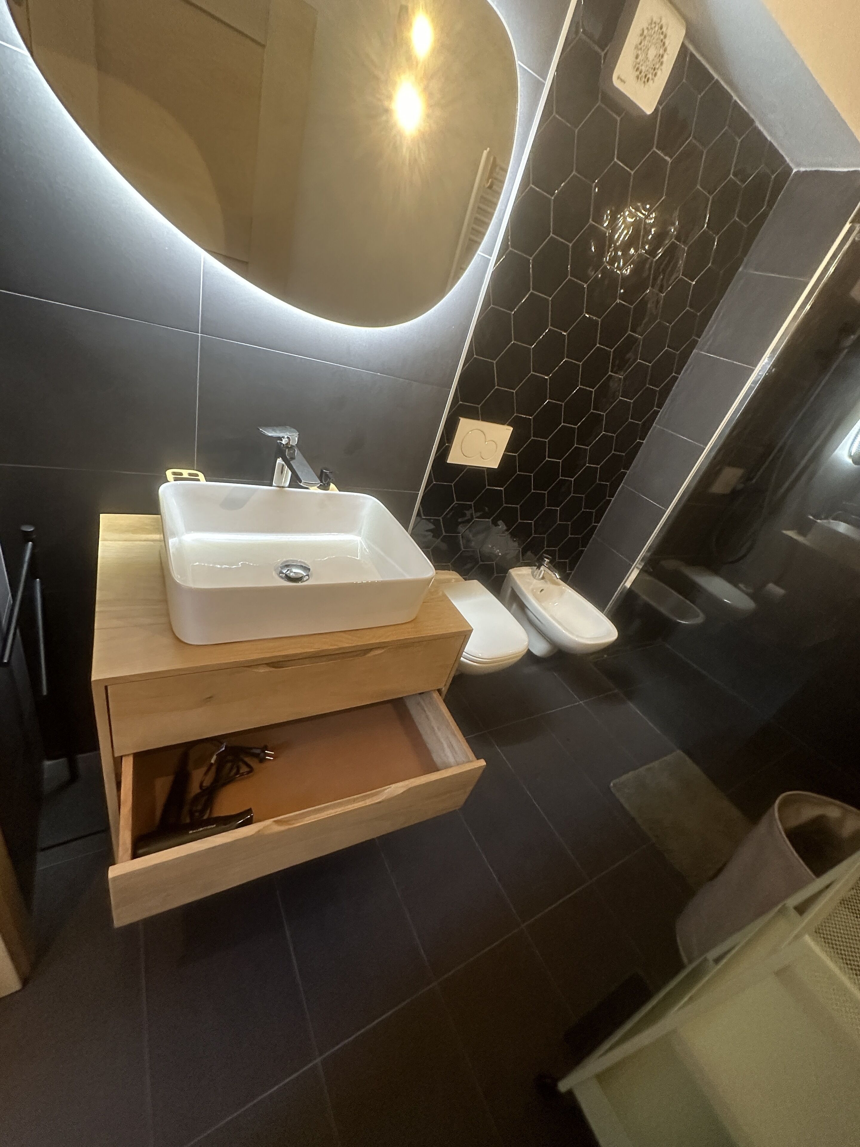 A modern bathroom with a large mirror, a sink, a toilet, and a shower area.