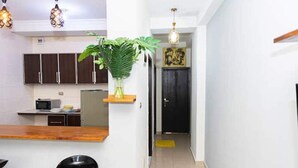 Una cocina con armarios de madera oscura, un microondas y una planta en maceta sobre una estantería.
