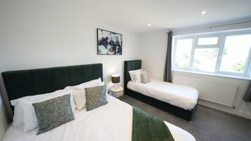 Quarto de hotel com duas camas, um quadro grande na parede e uma janela com cortinas.