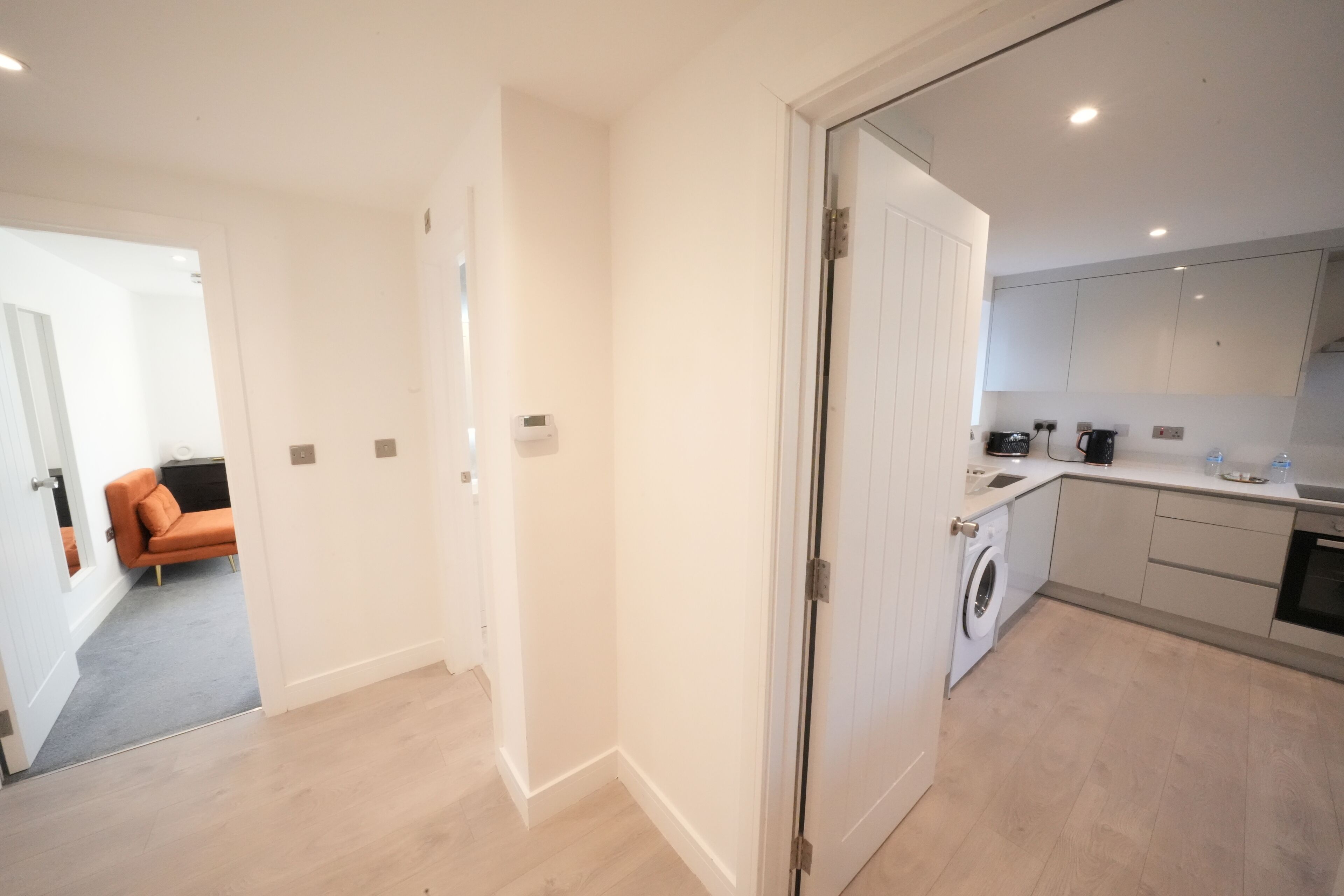 Un apartamento moderno con cocina, lavadora y sala de estar con sofá.