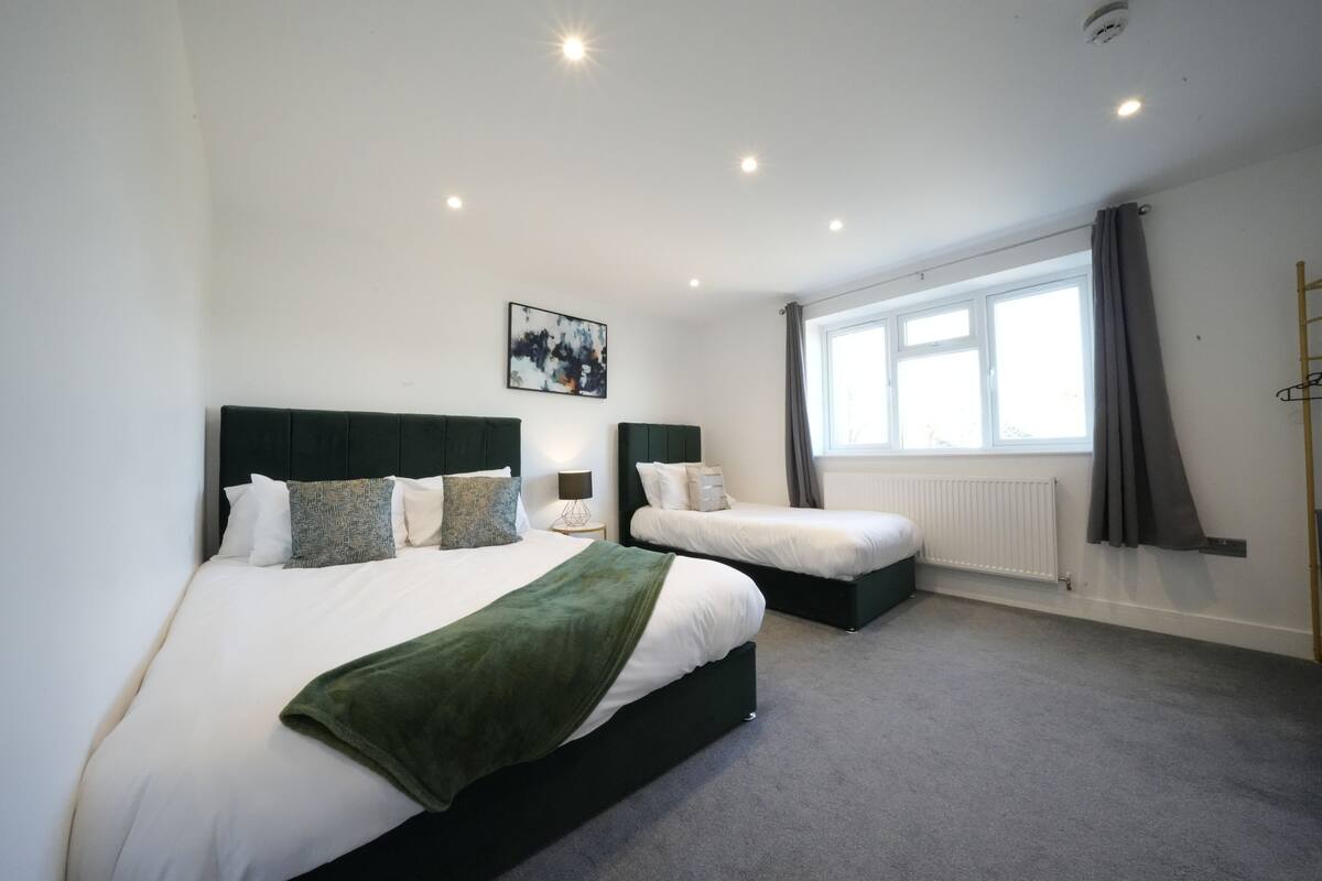 A hotel room with two beds, a large window, and a painting on the wall.