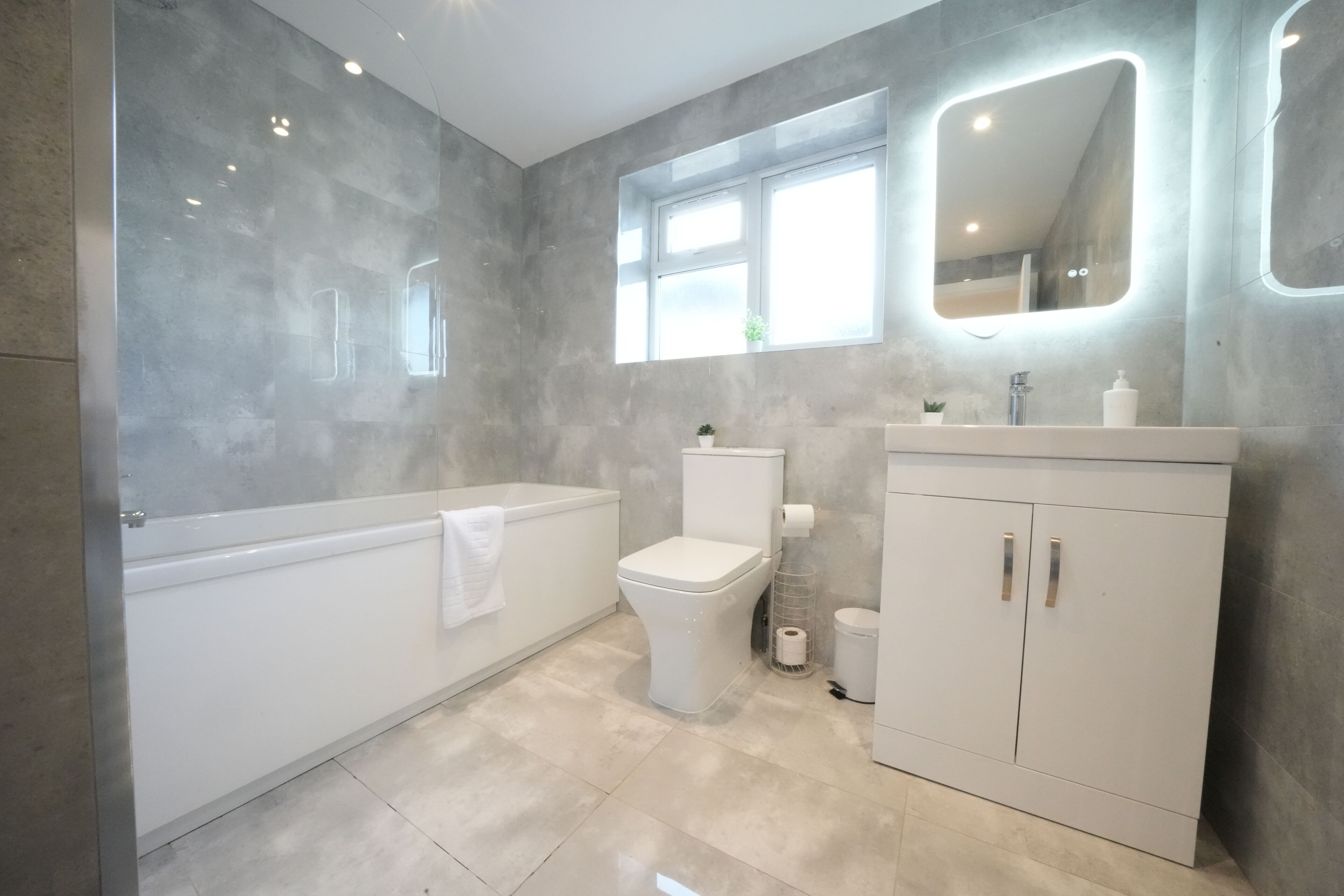 A modern bathroom with a bathtub, toilet, and vanity with cabinets.