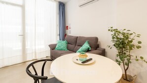 A modern living room with a brown sofa, a round table, and a potted plant. - Santa Pola Suites (Santa Pola)