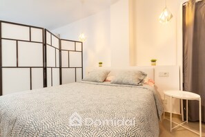 A bedroom with a bed, bedside tables, a small table, and a decorative partition. - Santa Pola Suites (Santa Pola)