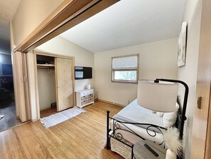 A bedroom with a bed, a bedside table, a TV, a window, and a closet. - Sunflower Retreat (Hutchinson)