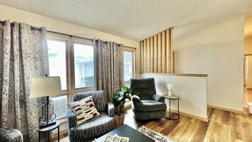 A living room with a sofa, armchair, coffee table, and a small side table.