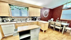 Una cucina compatta con mobili in legno, piano cottura integrato e zona pranzo con tavolo e sedie.