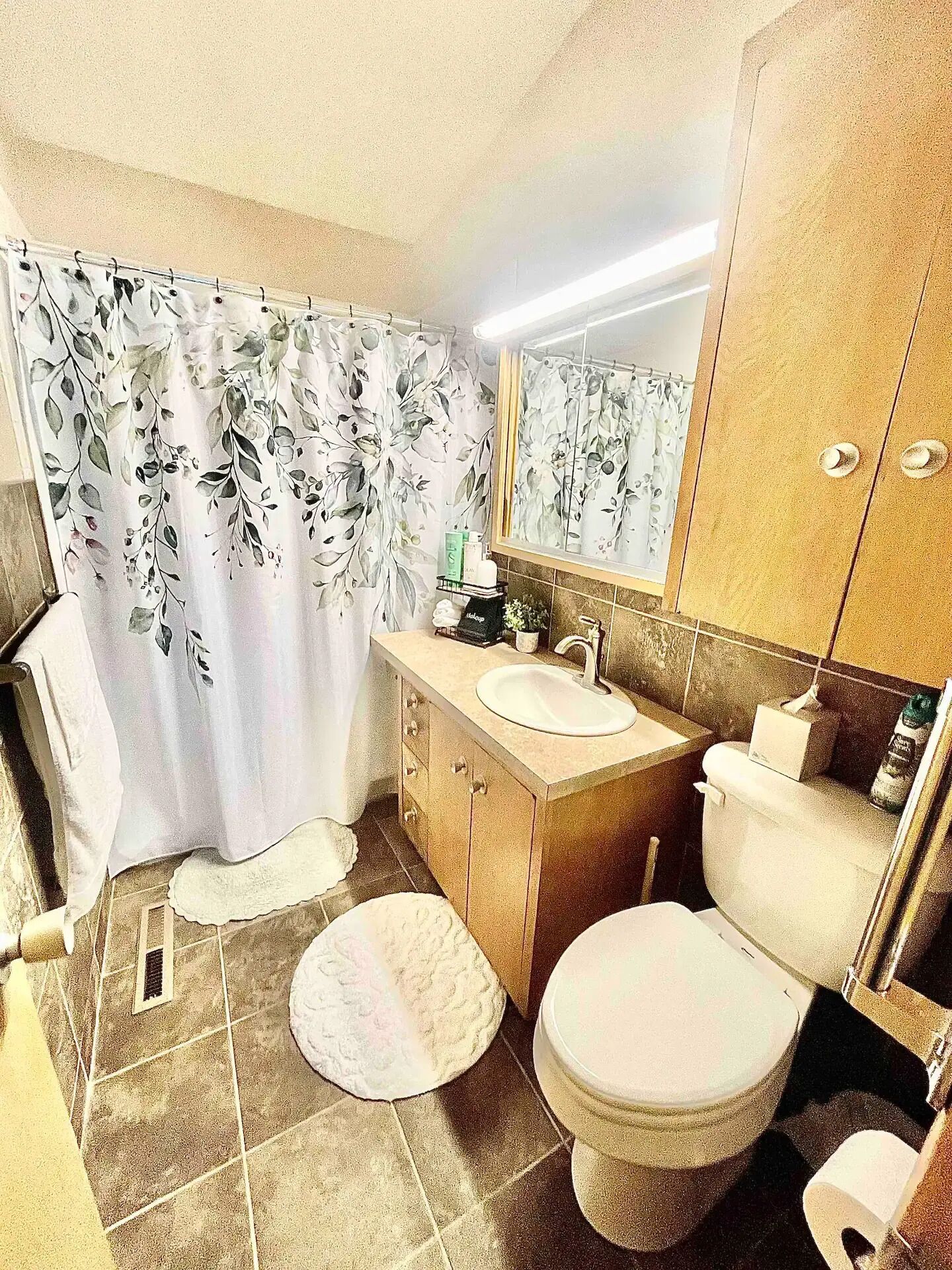 Un bagno con tenda doccia, lavandino, WC e specchio.