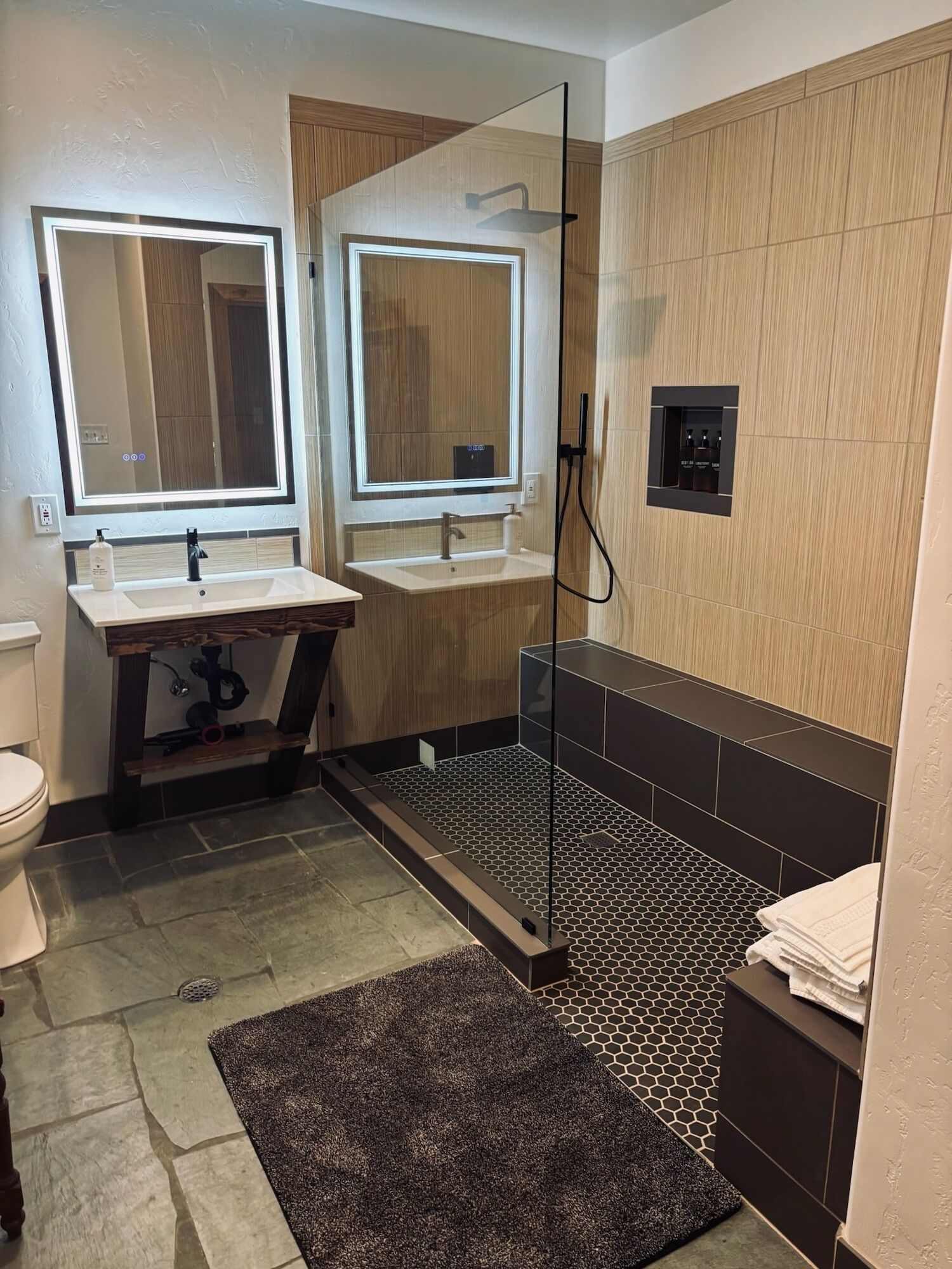 Un baño moderno con dos lavamanos, inodoro y zona de ducha.