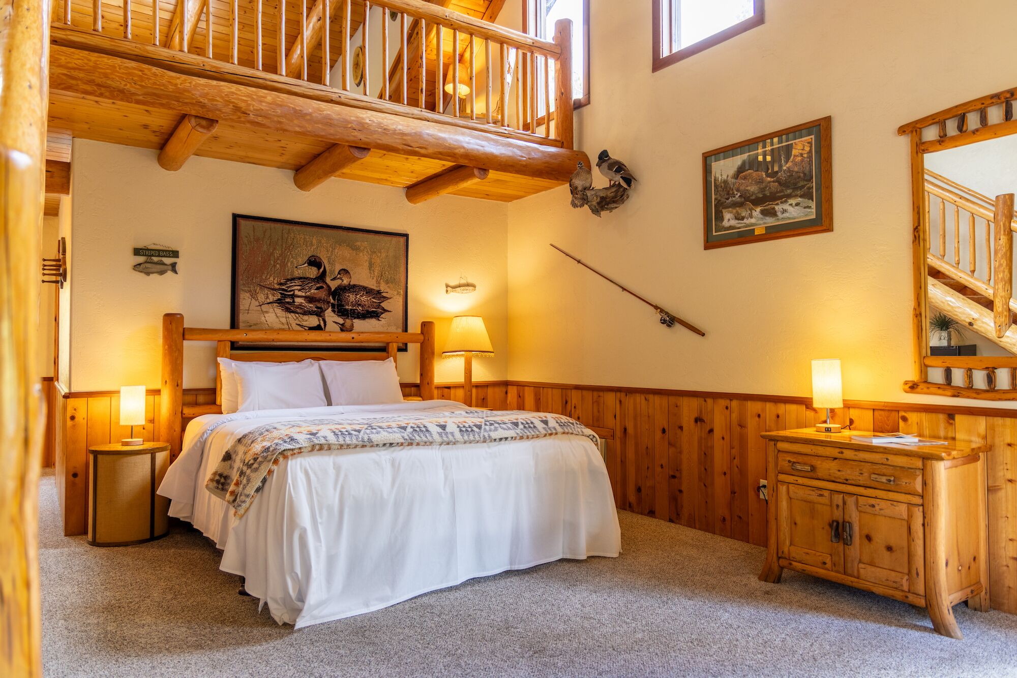 A cozy room with a wooden bed, a nightstand, a dresser, and a painting of ducks on the wall.