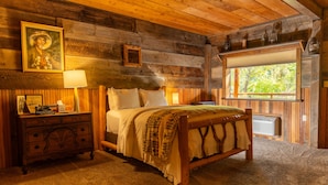 Une chambre à coucher rustique en bois, avec un lit, une table de chevet, une lampe et une fenêtre.