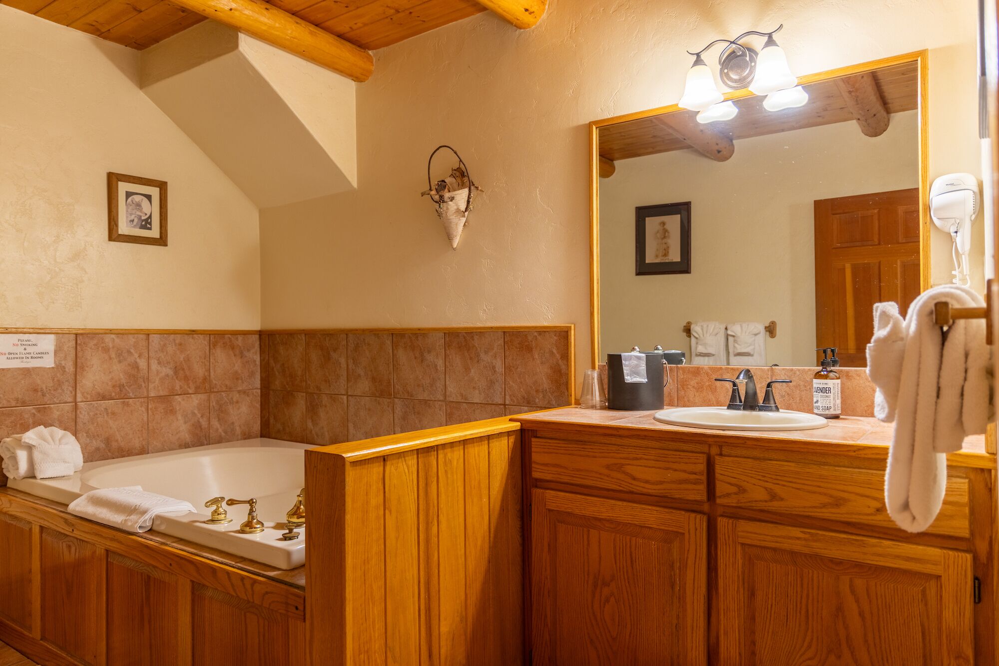 A bathroom with a wooden vanity, a bathtub, a sink, and a mirror.