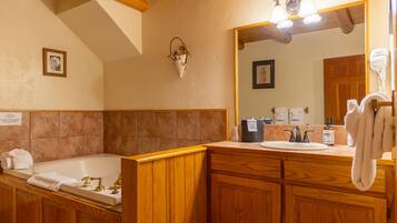 A bathroom with a wooden vanity, a bathtub, a sink, and a mirror.