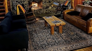 Un salon chaleureux avec une cheminée en pierre, des meubles en bois et un tapis à motifs.