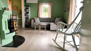 A living room with a sectional sofa, a rocking chair, a small table, and a bookshelf. - Idyllic cottage on a farm with fantastic views and surrounded by nature.  (Tretten)